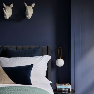 dark blue bedroom with black bed and trophy heads on wall
