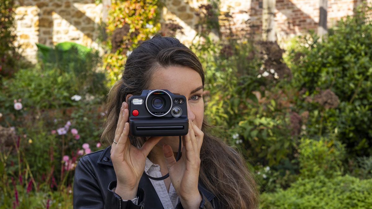 A female photographer holding the Polaroid I-2 instant camera up to her face and looking through the viewfinder