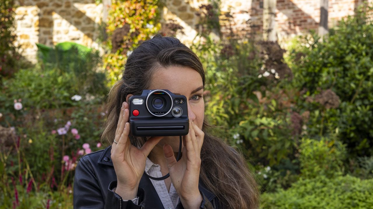 A female photographer holding the Polaroid I-2 instant camera up to her face and looking through the viewfinder