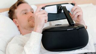 Someone lying down with a gaming handheld, using the Mechanism Gaming Pillow to hold it aloft