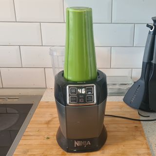 Ninja food blender on kitchen side blending up a green smoothie