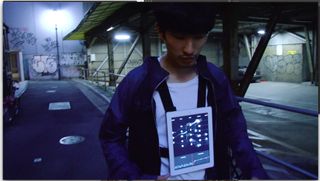 Still from a video featuring Yosuke Ushigome with a screen hanging from his neck