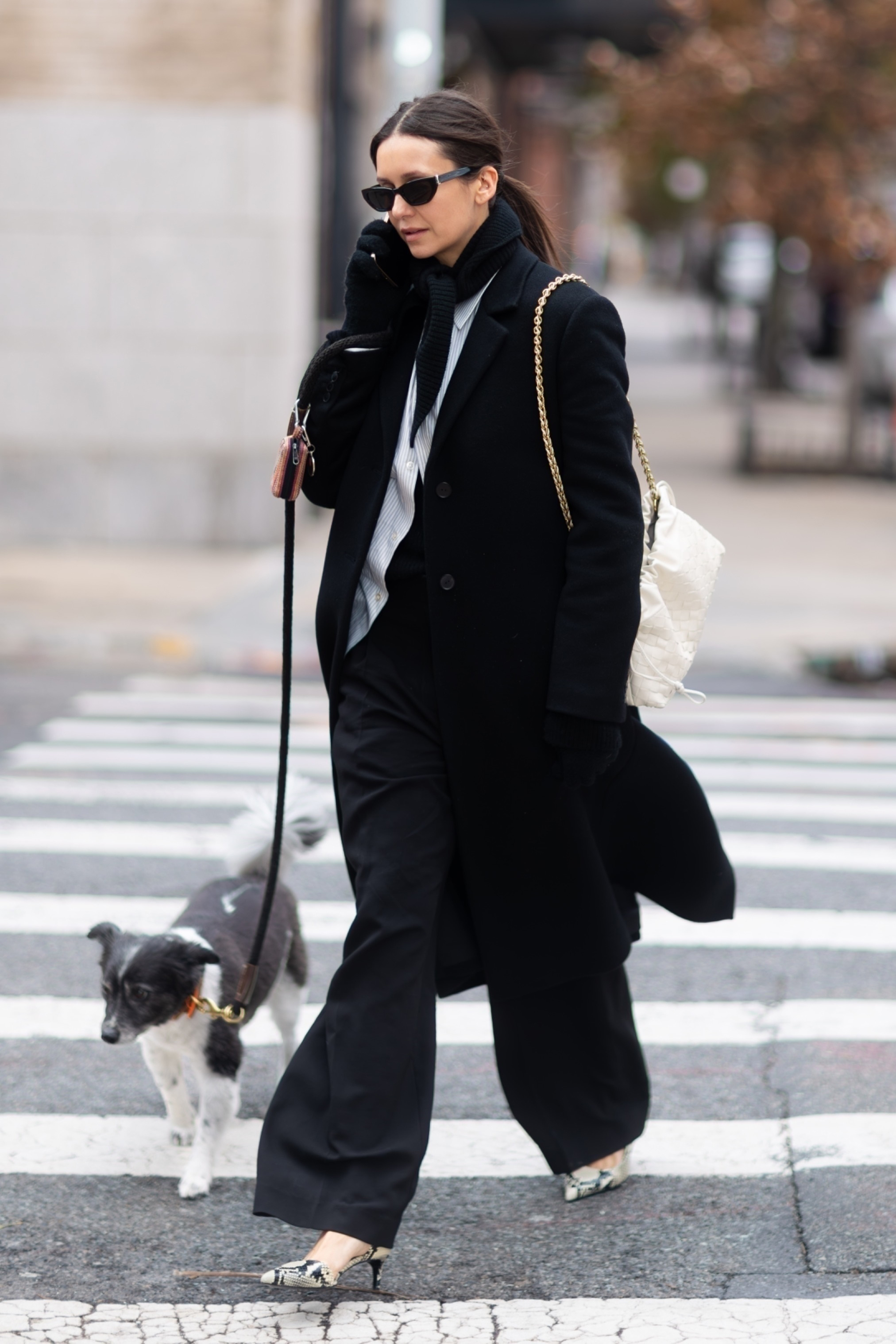 Nina Debrov wearing a black coat, white striped button down, black scarf, and snakeskin shoes