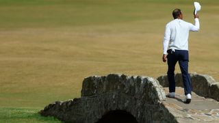 Tiger Woods acknowledges the crowd as he crosses the Swilcan Bridge at St Andrews during the 150th Open