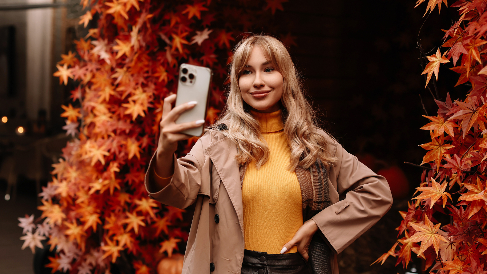 A person holding an iPhone, in front of a Fall-like background