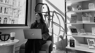 image of a woman with a laptop with a bookcase behind her