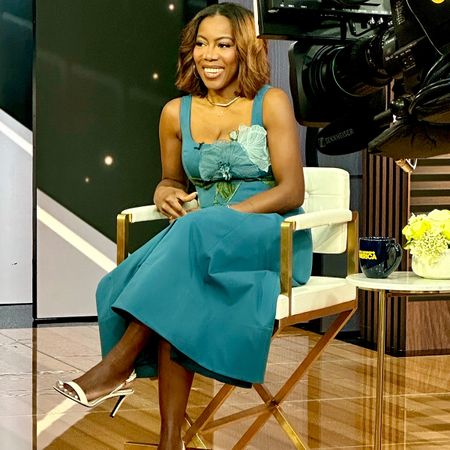 Who What Wear Editor in Residence Tiffany Reid wearing a blue floral dress and white heels while shooting a television segment. 