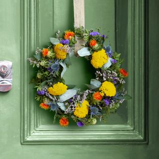 A colourful wreath on a green painted front door