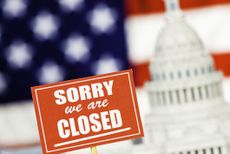 sorry we are closed sign in front of a rendering of the US capitol building