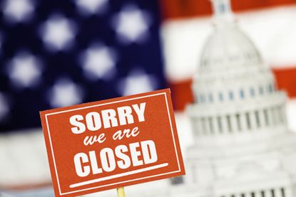 sorry we are closed sign in front of a rendering of the US capitol building