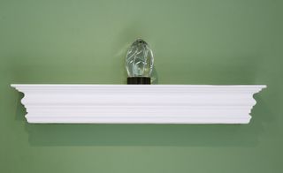 Green wall, white shelf with crystal ornament