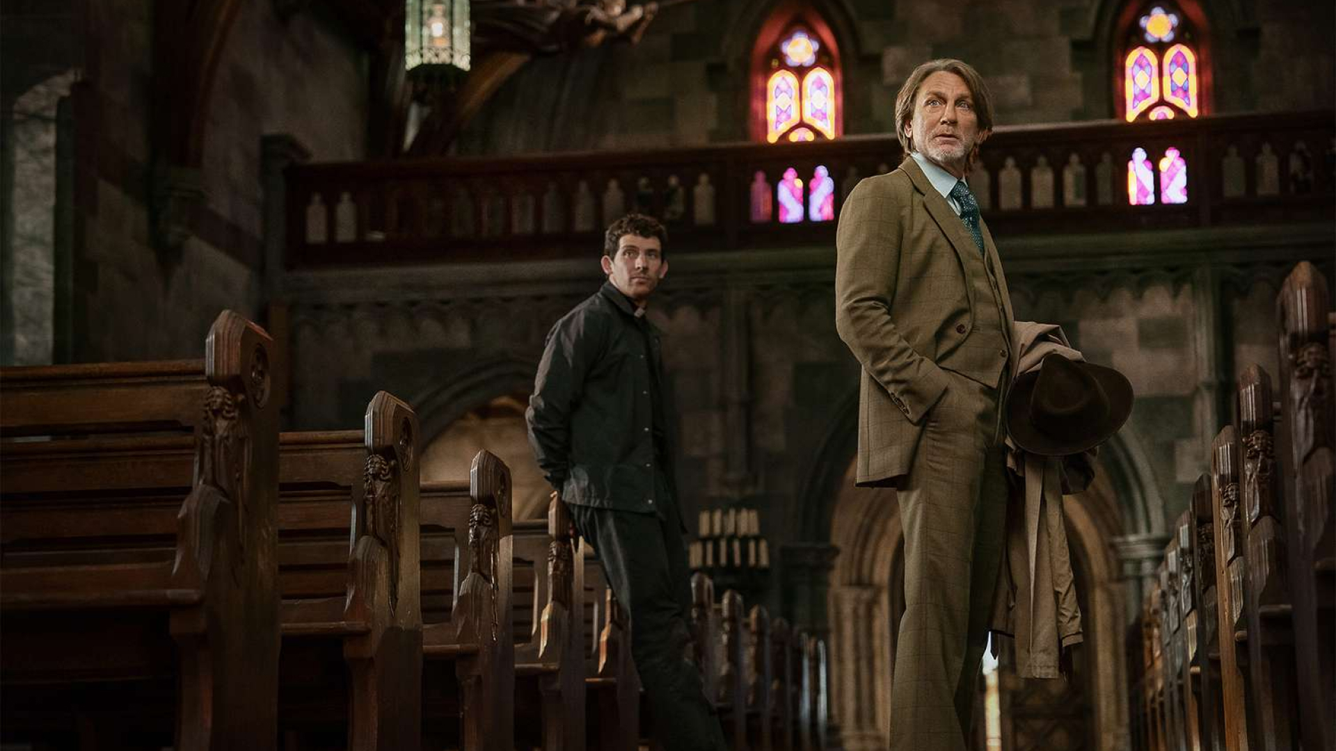 josh oconnor as a priest and daniel craig as benoit blanc standing in a church in wake up dead man a knives out mystery