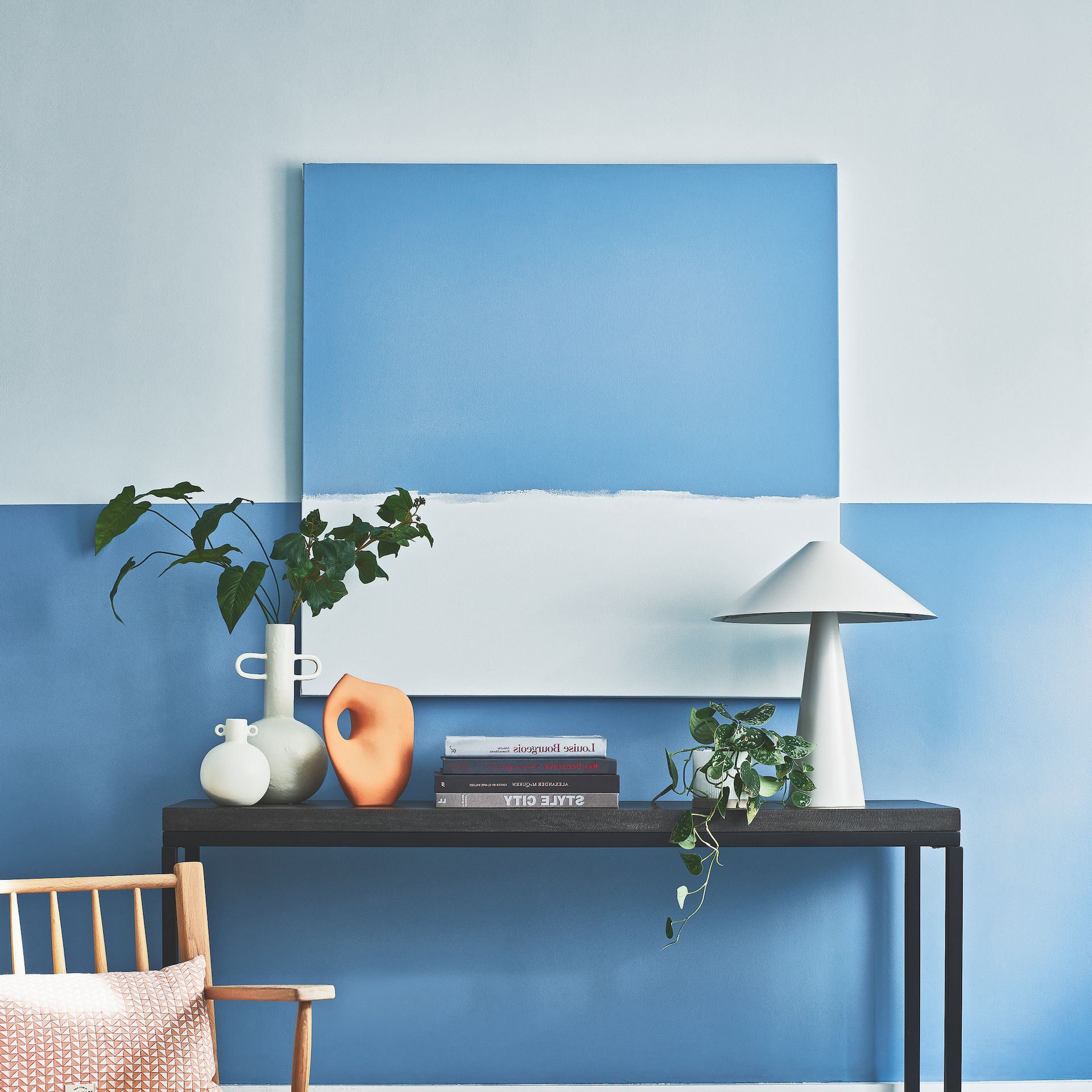 home office with two-tone paint wall and books on desk with lamp