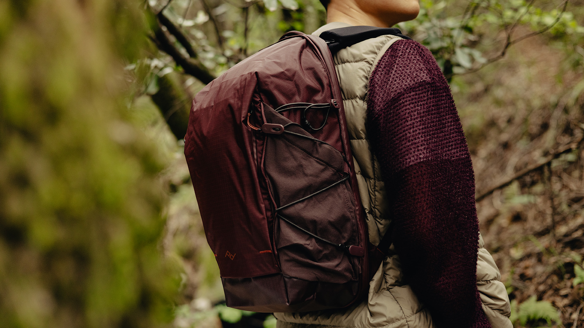 Peak Design Outdoor Backpack 18L in Eclipse on back of person walking through forest 
