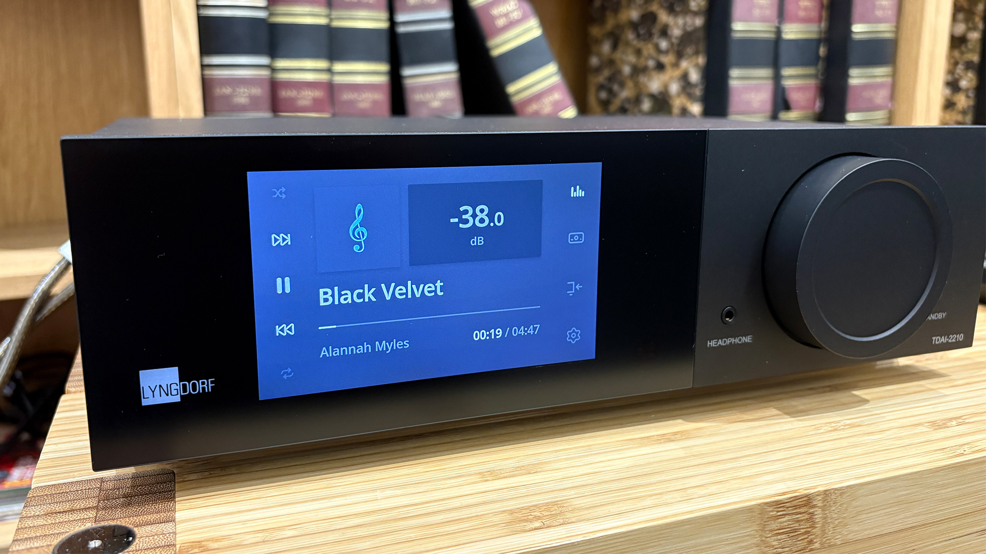 Lyngdorf TDAI-2210 streaming amplifier on wooden hi-fi rack in front of bookcase