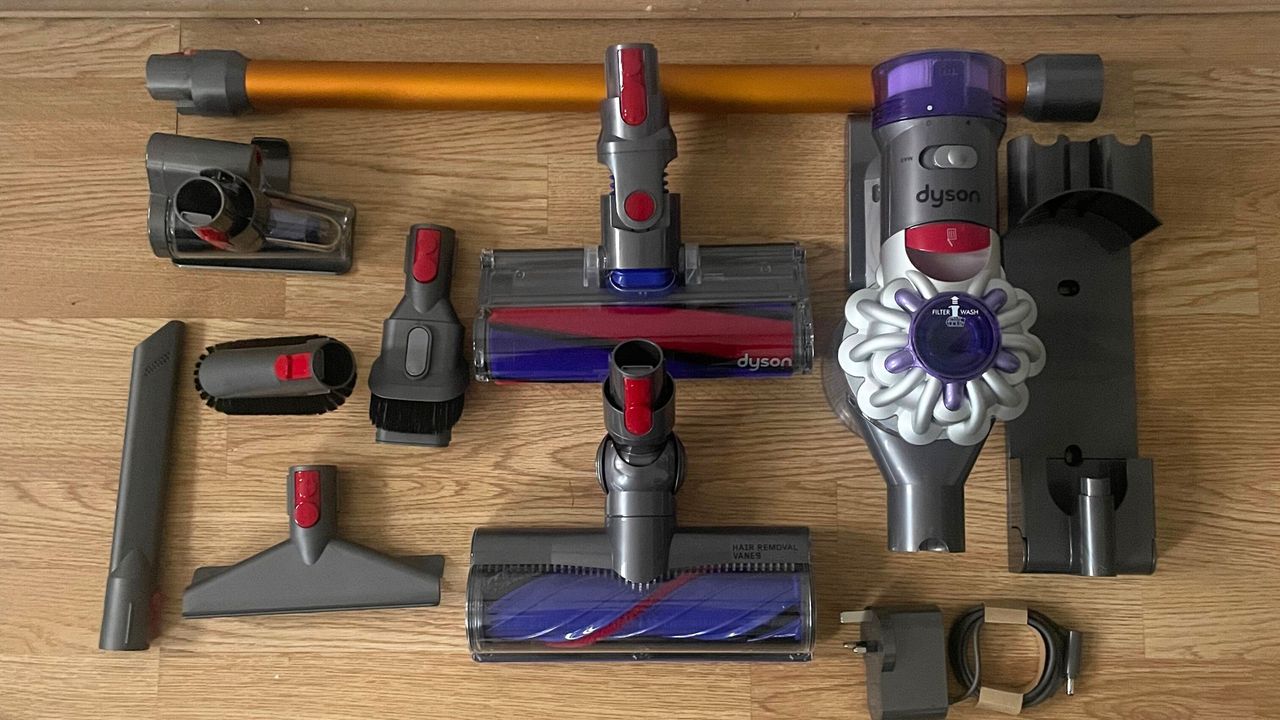 Dyson V8 Absolute vacuum cleaner in pieces on wooden floor surrounded by numerous attachments