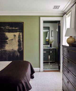 Green bedroom looking to bathroom with painting on wall