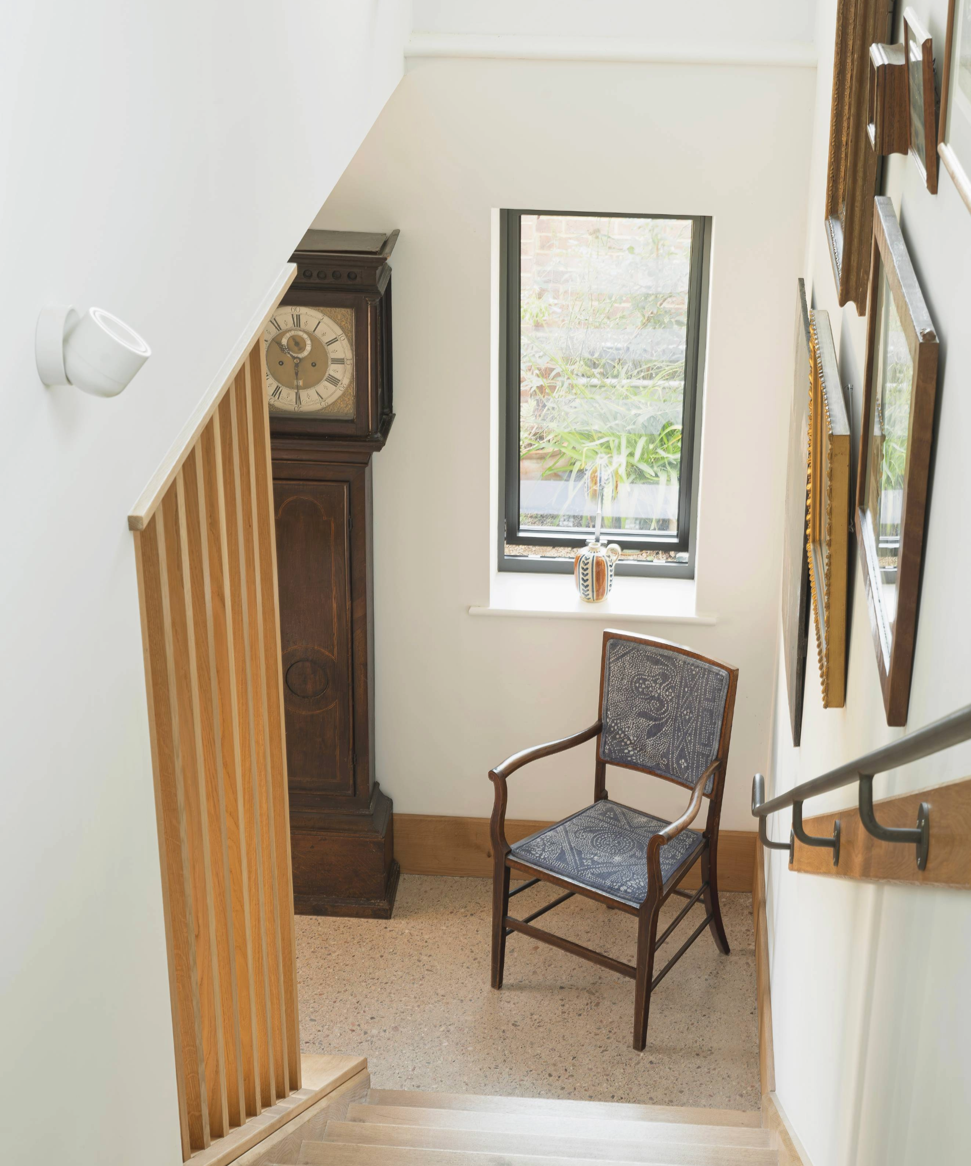 View from the top of the staircase with a window and chair at the bottom