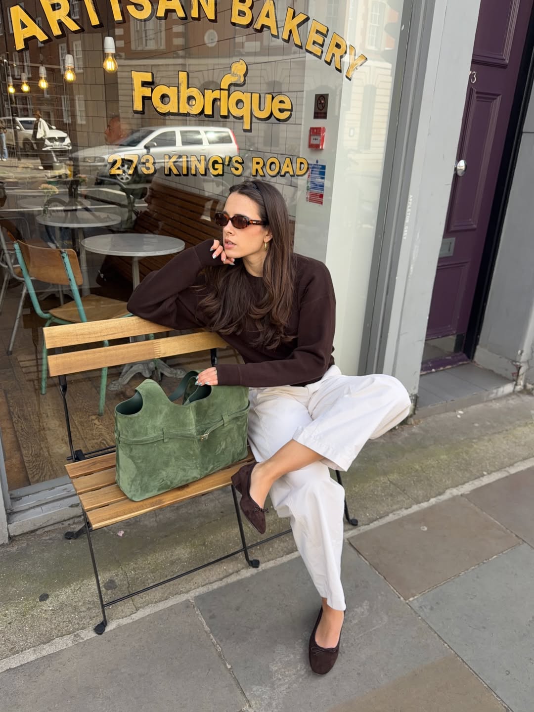 tia dewitt wears a brown top, white trousers, ballet flats and manu atelier cambon bag