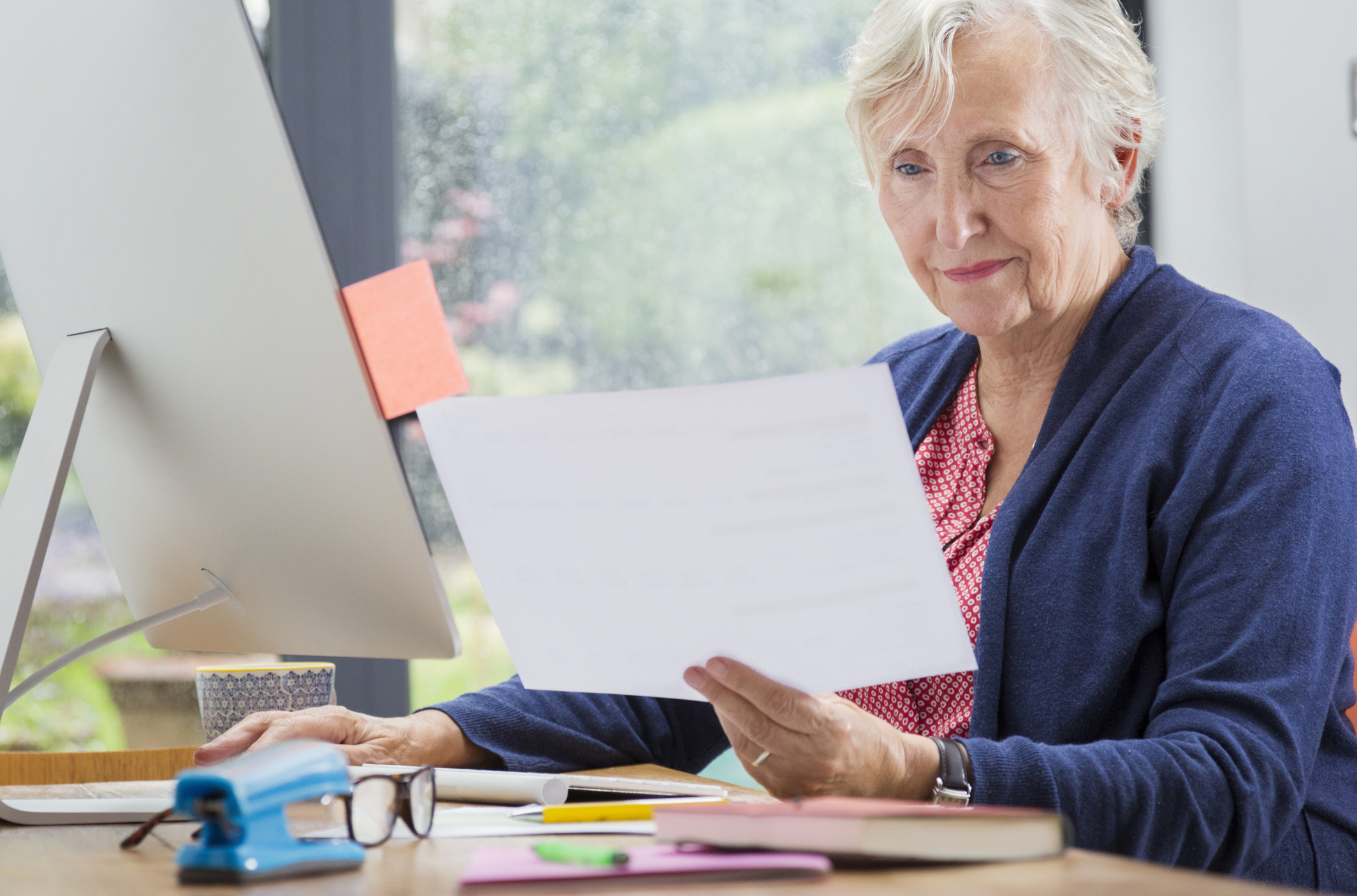 Female pensioner reading financial and tax paperwork
