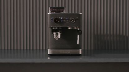 Image of a black KitchenAid espresso machine on a gray countertop in a kitchen that has a gray fluted backsplash.