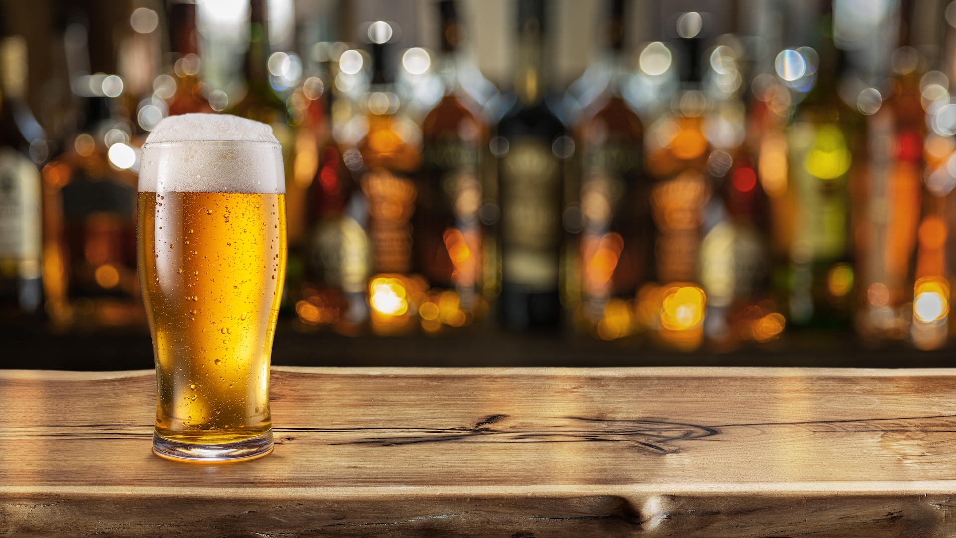 A photo of a full glass of beer on a bar counter