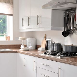 kitchen with sleek white gloss units teamed with vintage style storage tins and storage jars