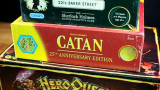 A stack of classic board games sitting on a wooden table