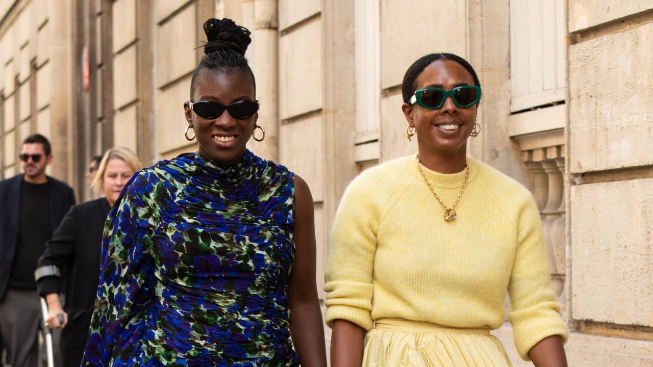 Nikki Ogunnaike wears a Dries Van Noten top, black jeans, Prada shoes and sunglasses with Nicole Martine Chapoteau wearing a Sezane jumper