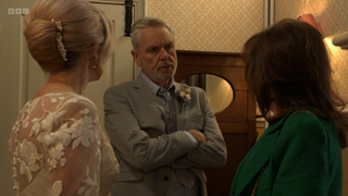 An angry Rocky Cotton with his arms crossed as he and Kathy Beale confront Jo Cotton during their wedding.