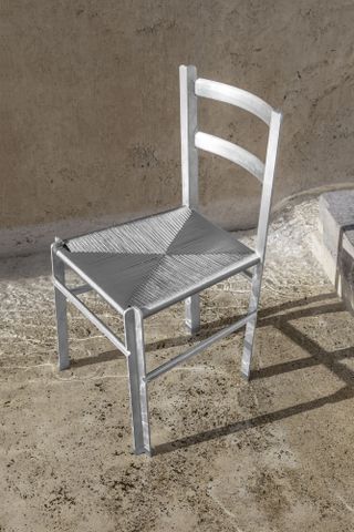 Silver chair with a woven seat on a concrete floor