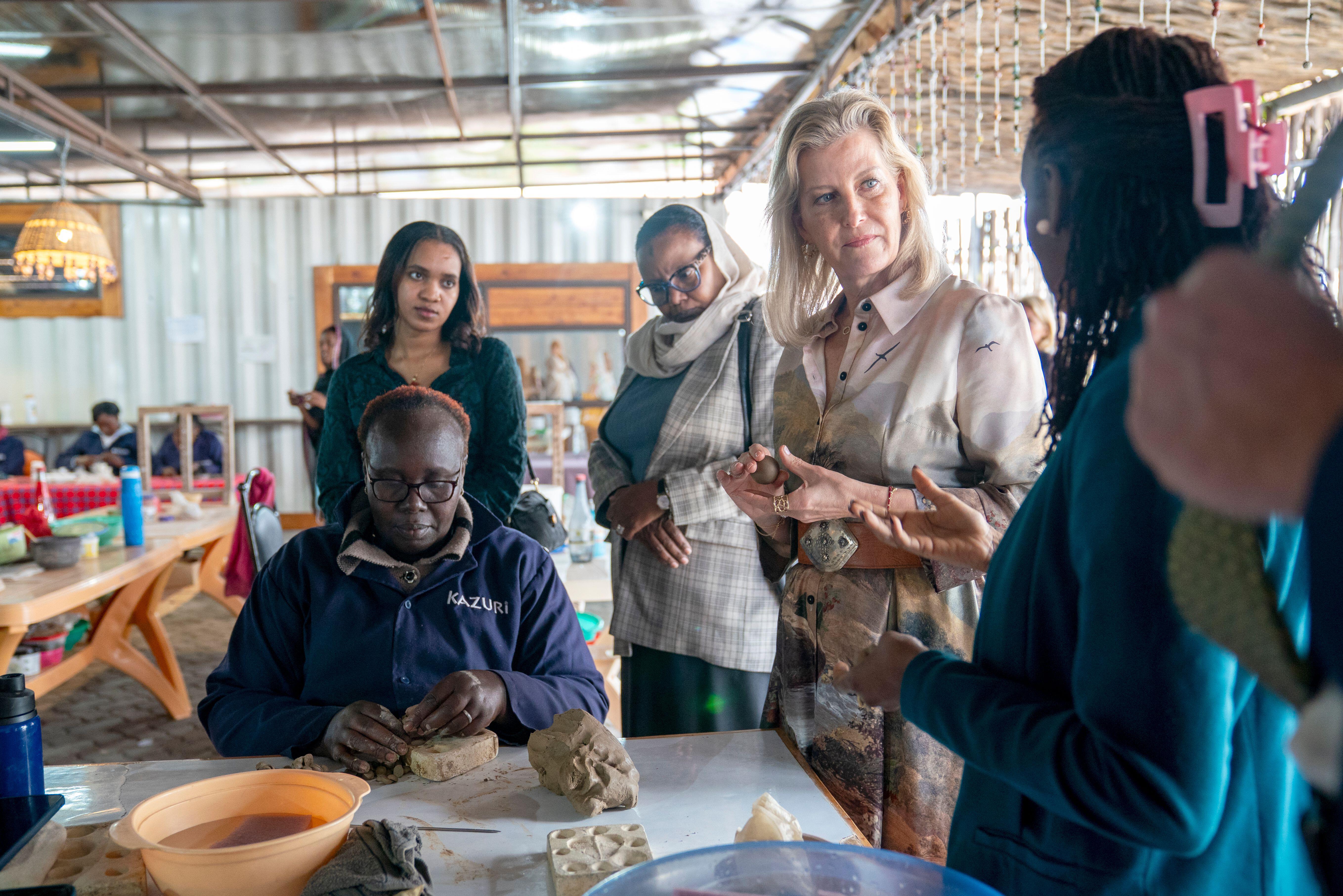 Duchess Sophie standing at a table while a woman makes beaded jewelry