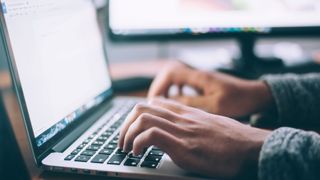 Person writing on a laptop