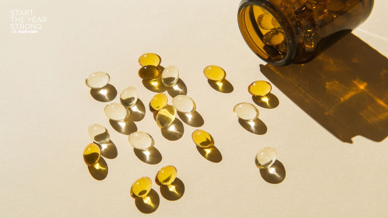 A flat lay of some supplements in a glass jar bottle spilling onto a yellow background