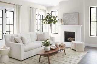 A living room with off-white walls, a natural rug, and a cream sofa