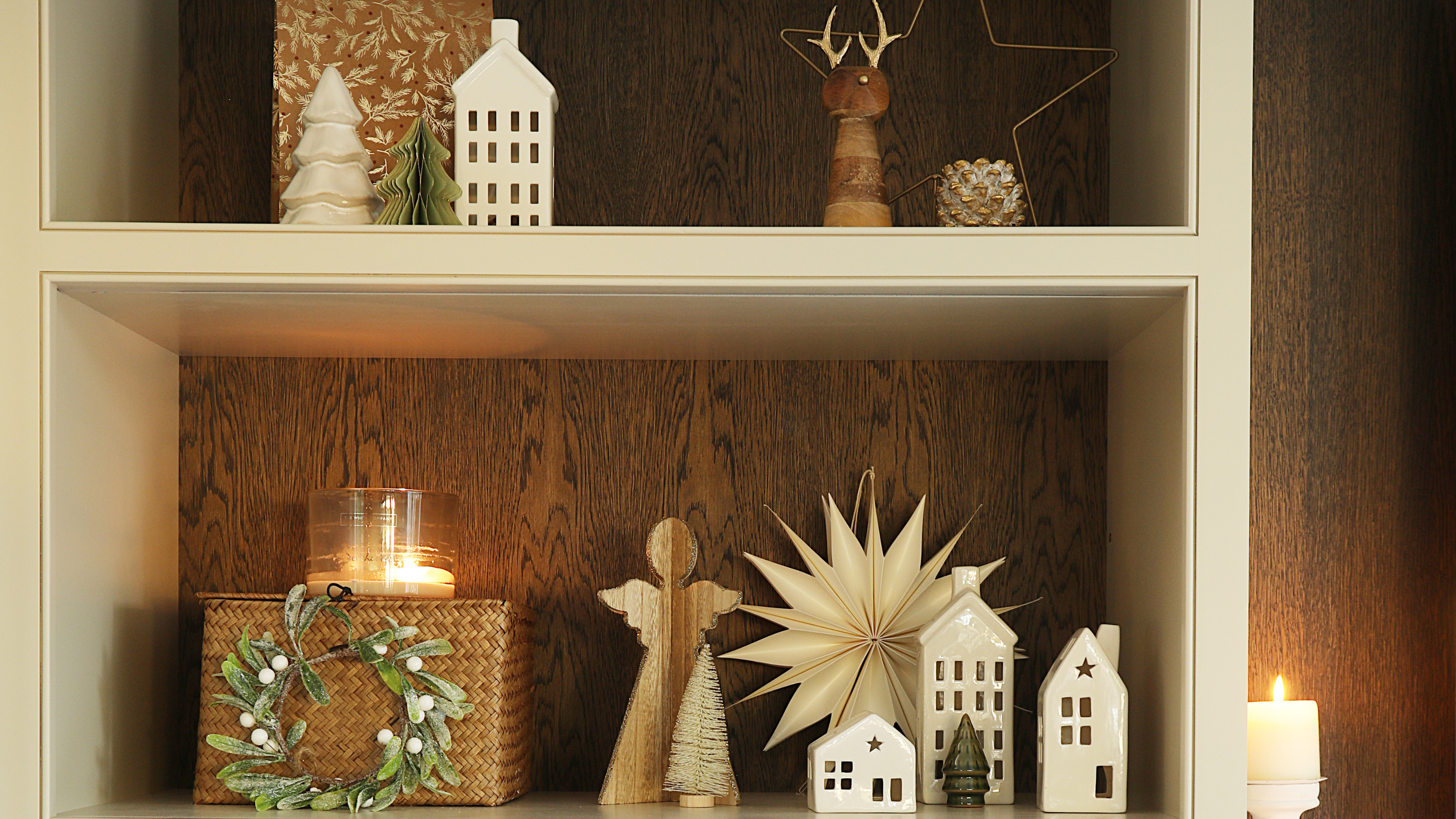 Ceramic Christmas light up houses on a wooden shelf.