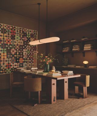 office with brown painted walls and tapestry on walls and jute rug and low hanging strip pendant light