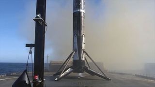 The first stage of a rocket stands upright on its four legs atop an ocean-based droneship, soon after launching to space.