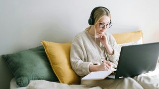 A free to use image from Pexels, taken by photographer Ivan Samkov, showing a woman working on a laptop while wearing headphones