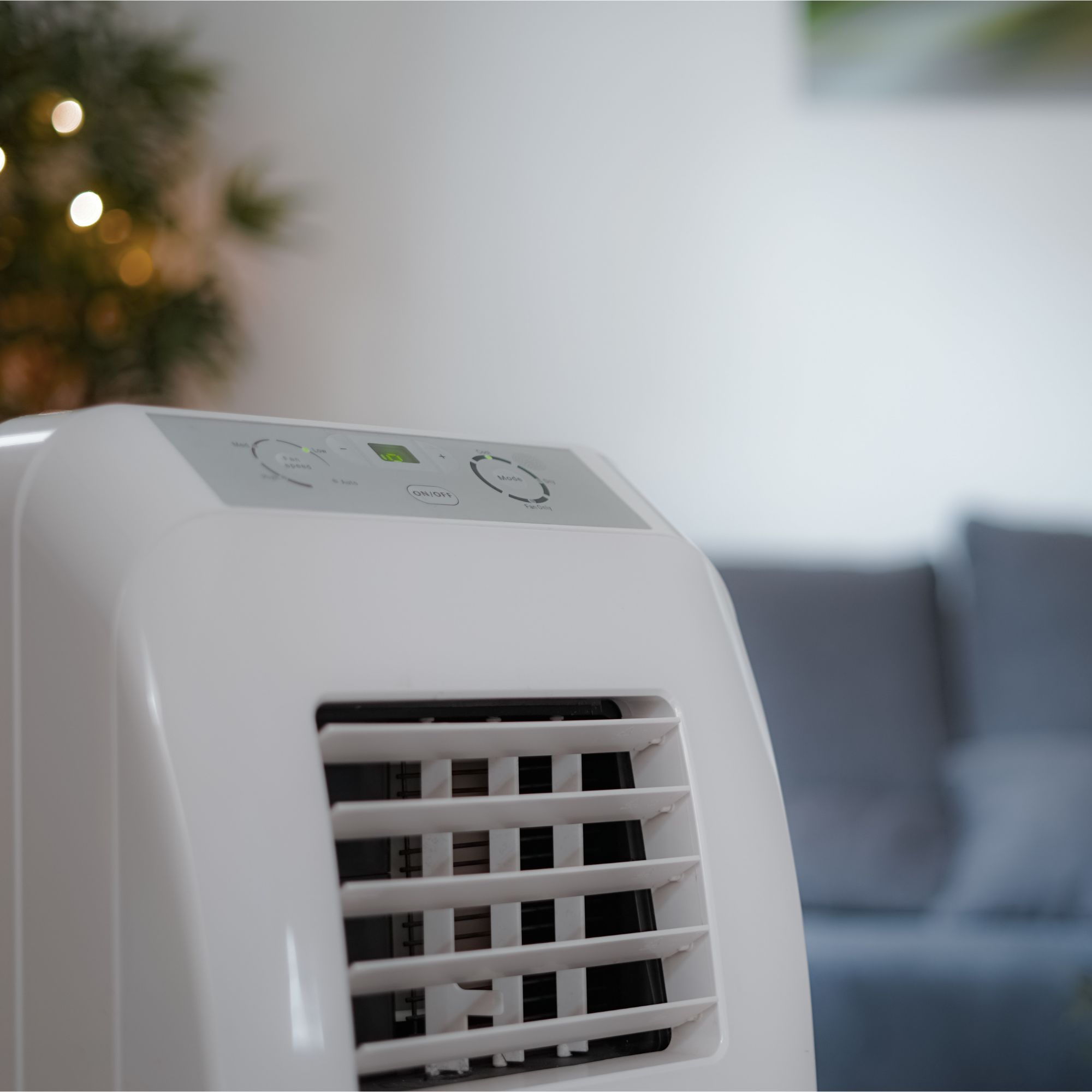 Close up of a portable air conditioner with a blue sofa in the background