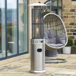 A silver gas patio heater in front of a hanging egg chair