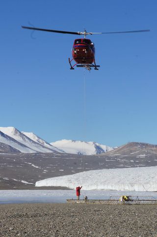 A scientist prepares an airborne electromagnetic mapping sensor for a survey flight near Lake Fryxell in the McMurdo Dry Valleys, Antarctica.