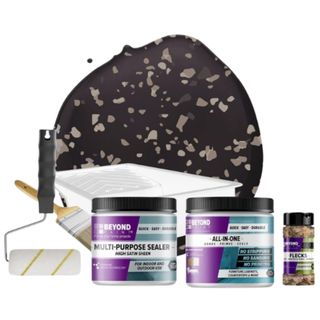 Beyond Paint Countertop Makeover Refinishing Kit, Charcoal which showed a pool of dark paint with flecks plus roller and bottles of product and flecks