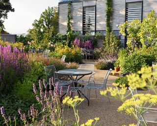 Mixed borders of culinary herbs and edible flowers grown for taste but also their ornamental properties surround tables