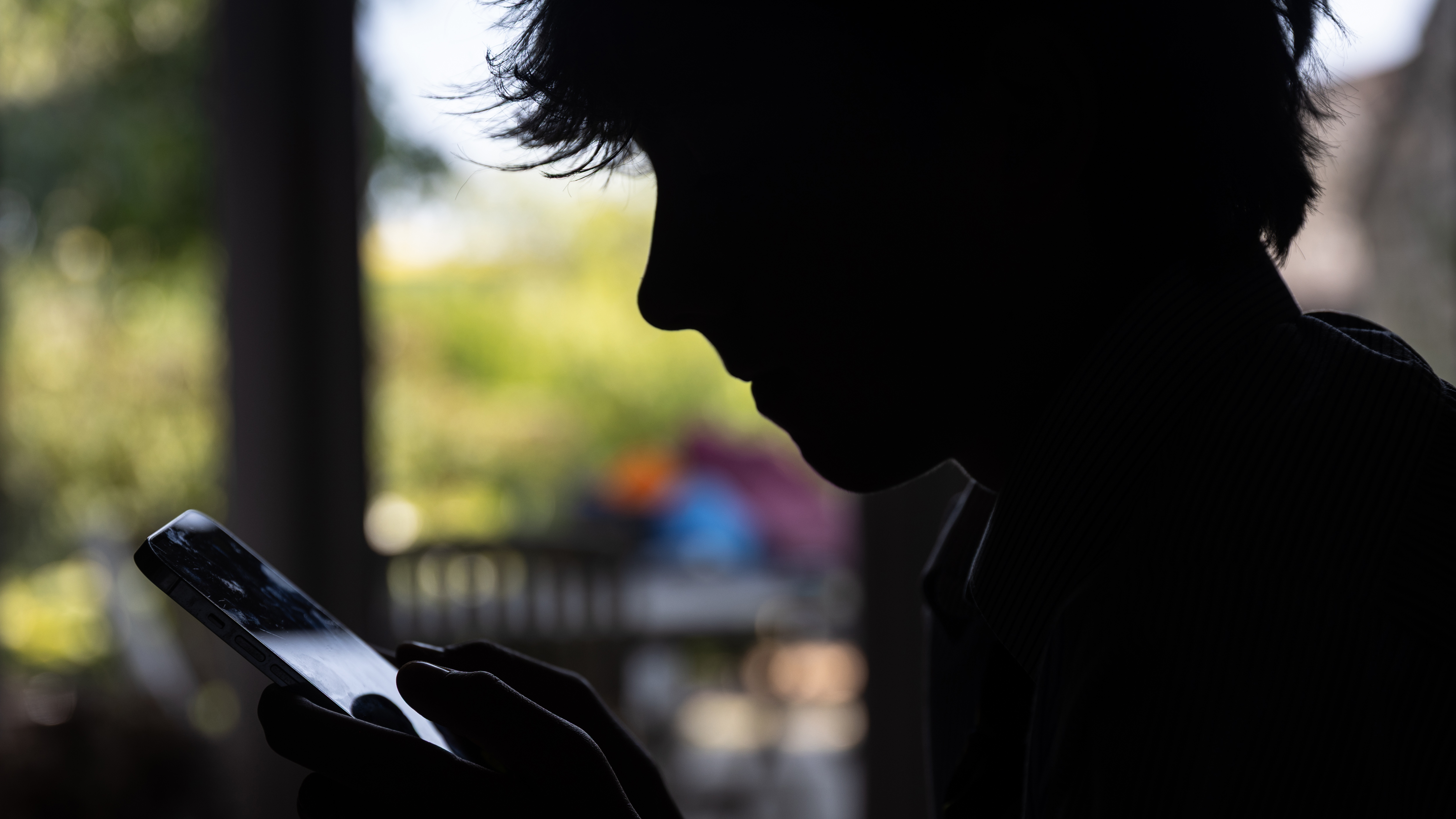The silhouette of a child looking at a smartphone