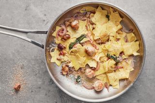 Jamie Oliver's Christmas pasta in a frying pan: the pasta has been cut into star shapes and is served with bacon, sausage, red onion, basil and parmesan cheese