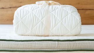 The Avocado Mattress Pad Protector wrapped in a neat bundle and tied with a white satin ribbon
