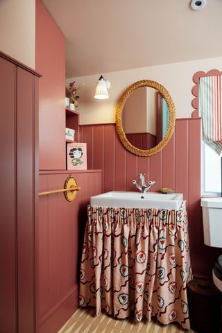 Bathroom basin with skirt and warm red tongue and groove paneling with neutral wall above