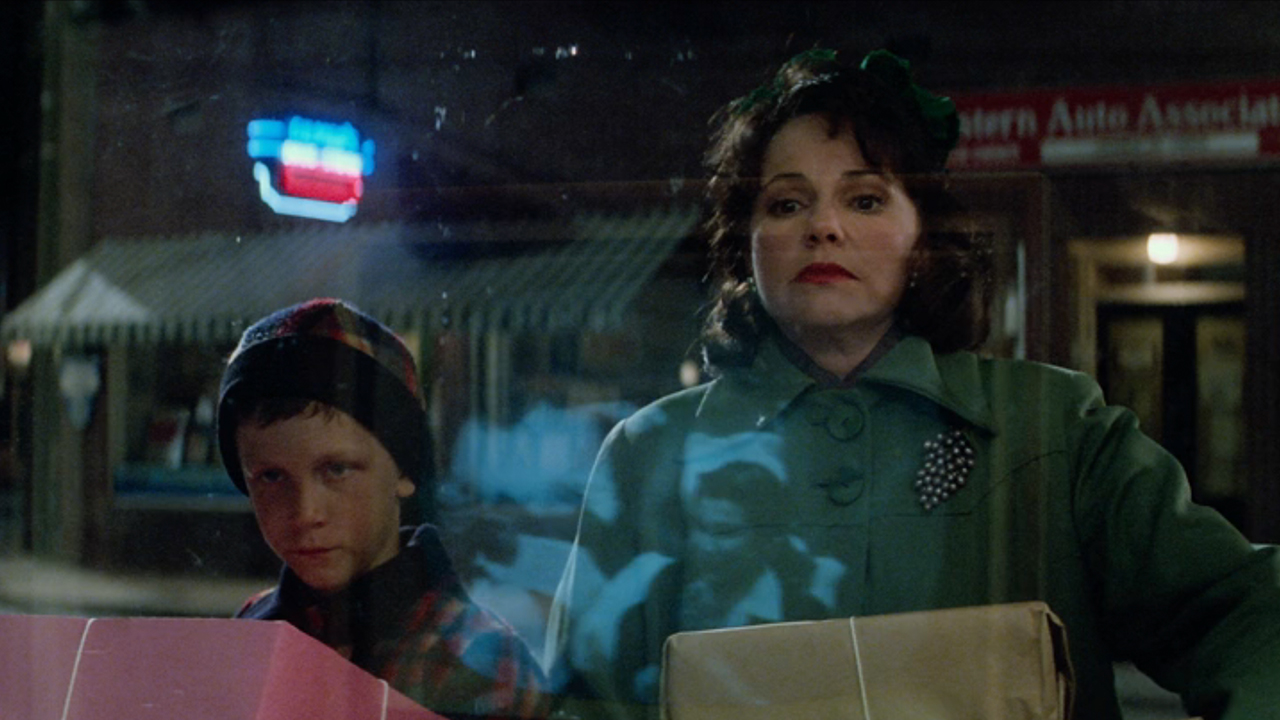 Sally Field and a young Forrest Gump looking in the window of a store with the reflection of Elvis Presley on TV