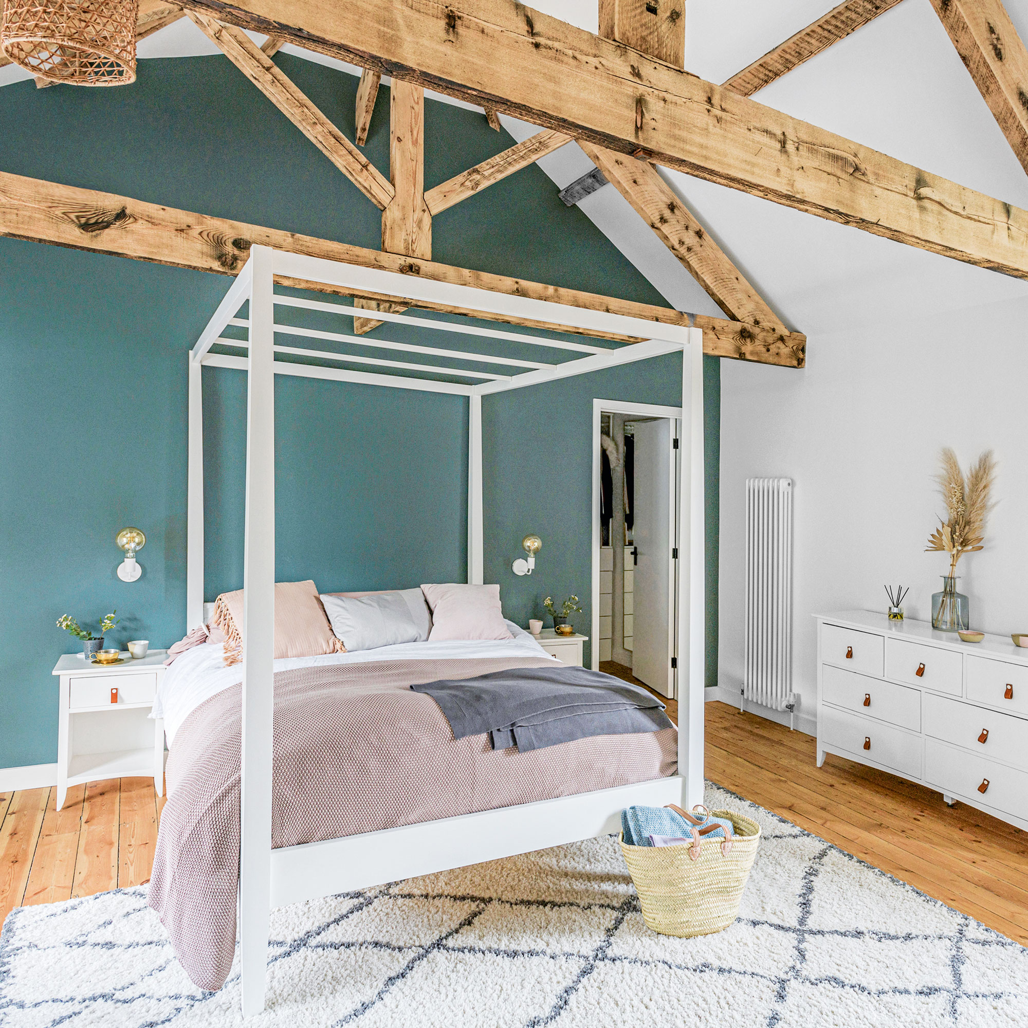 blue bedroom with white four-poster bed, wooden floor, rug and wooden beams